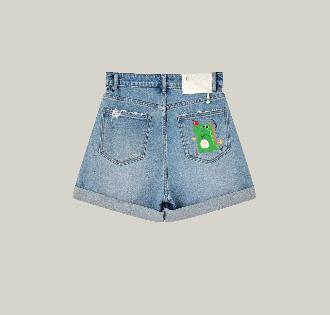 A pair of denim shorts featuring a cute little dinosaur print—an essential item for your summer wardrobe.